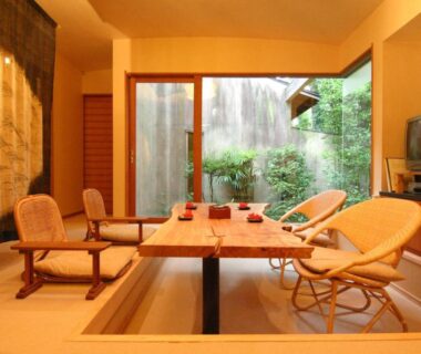 Tatami room with sunken seating, low table and sliding glass doors opening to a small garden at Hanafubuki Shizuoka