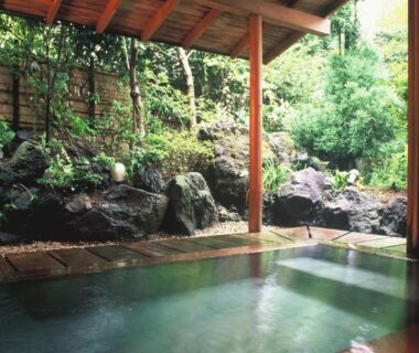 Wood-framed outdoor onsen facing a rock garden at Hanafubuki in Shizuoka