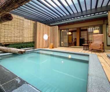 Enclosed covered onsen pool beside tatami room with shoji doors and wooden deck at Hanakanzashi in Fukushima