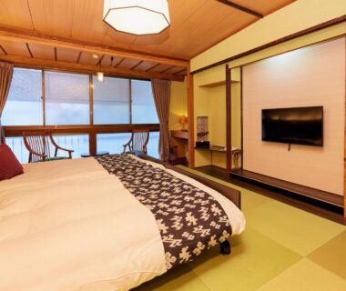 Twin beds on tatami flooring with low wooden ceiling, seating by large window in Hanakanzashi, Fukushima
