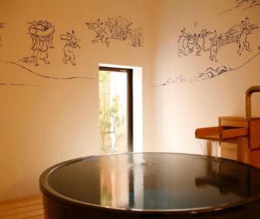 Indoor round soaking tub with mural-lined wall at Hanamandara ryokan in Hyōgo, Kansai