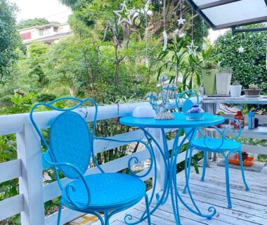 Blue metal bistro table and chairs on wooden deck with lush garden at Hanamizuki Onsen Resort, Shizuoka