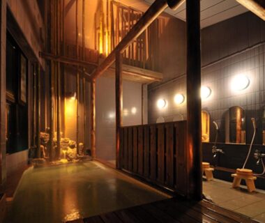 Warm-lit communal indoor bath with wooden tub and shower stools at Hanano Koyado Jyu-bei, Mie, Kansai