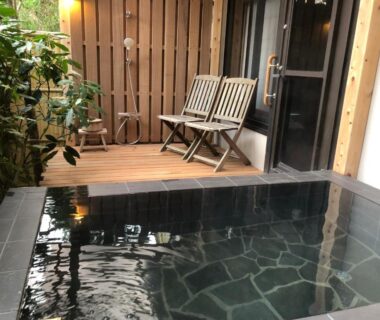 Stone bathing pool with wooden deck and chairs at Hananoyado Fukuya Kanagawa