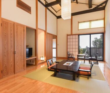 Spacious tatami room with low table, sliding shoji doors and balcony seating with outdoor view