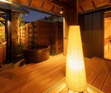 Outdoor wooden deck with round soaking tub, warm lantern light and screened privacy at Hanashibuki, Chiba, Kantō
