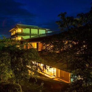 Lit wooden ryokan exterior with elevated corridor and surrounding trees at night in Mie, Japan