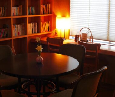 Intimate lounge with round wooden table, bookshelves and soft lamp lighting at Hanashinsui in Mie