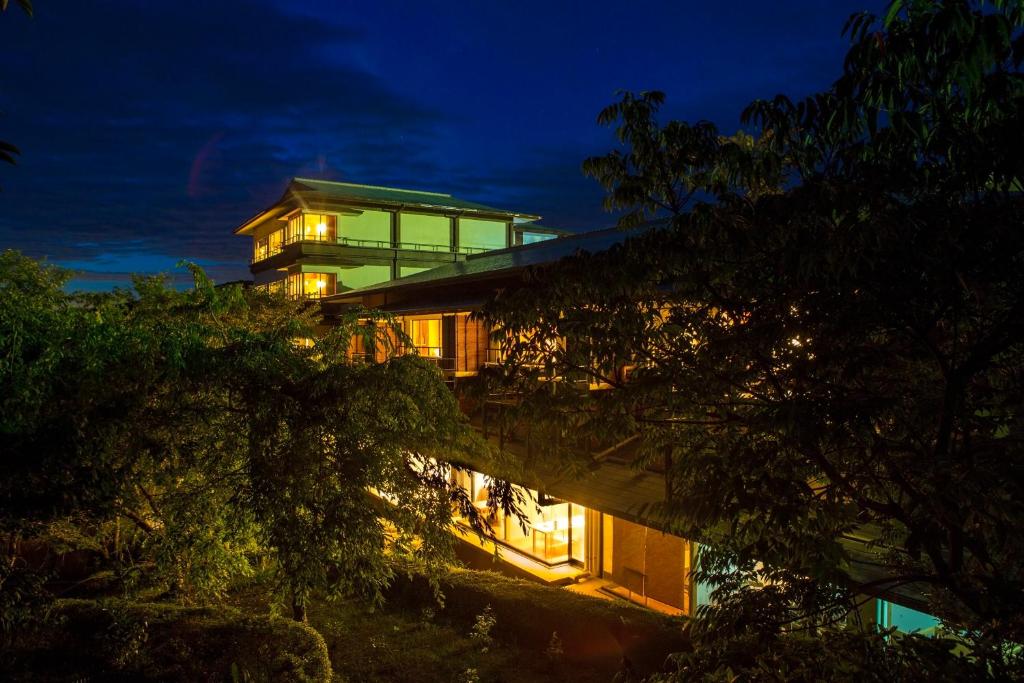 Nighttime illuminated ryokan Hanashinsui in Mie Lit wooden ryokan exterior with elevated corridor and surrounding trees at night in Mie, Japan