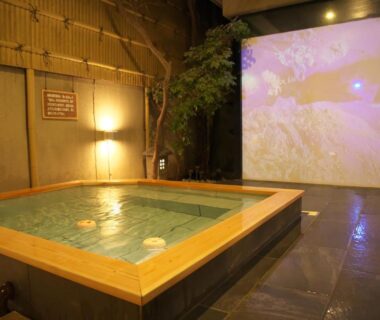 Wood-framed indoor onsen bath with projection screen at Hanasuishou in Yamanashi