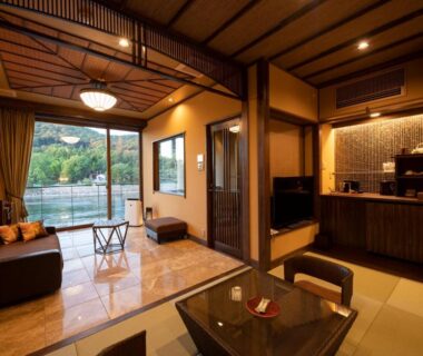 Tatami seating area with low table, sofa and balcony overlooking river at Hanayashiki Ukifune-en Kyoto Kansai