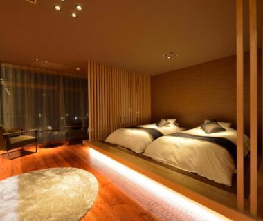 Twin beds with wooden partition and lounge area at Hanayashiki Ukifune-en, Kyoto