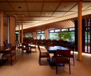 Spacious dining area with wooden tables and floor-to-ceiling windows overlooking garden at Hanayashiki Ukifune-en, Kyoto