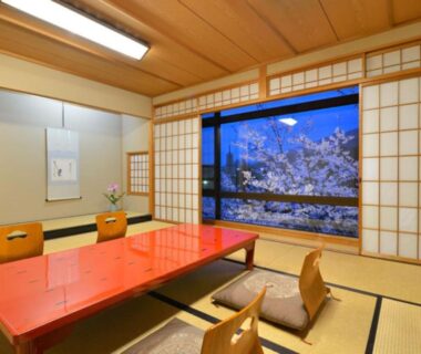 Traditional tatami room with lacquered low table, zabuton chairs, shoji screens and cherry blossom view at Hanayashiki Ukifune-en Kyoto