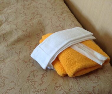 Folded orange and white towels on patterned bedding at Happokan in Nagano, Chubu, Japan