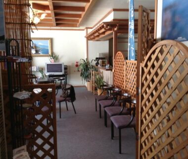 Interior waiting area with chairs, lattice screens, wooden beams and potted plants in a Nagano ryokan