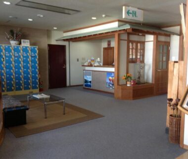 Reception counter with seating, tatami mat area and blue lockers at Happokan, Nagano