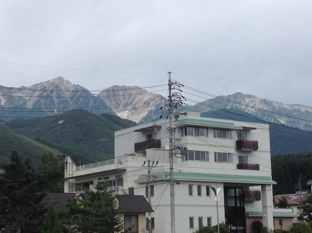 Exterior view of Happokan in Nagano White multi-story ryokan building with balconies and mountain range backdrop in Nagano, Chūbu