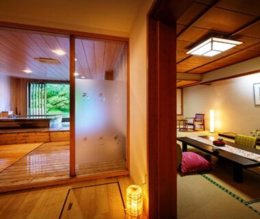 Traditional tatami seating and low table, sliding doors opening to a wooden bath area and garden view at Harataki, Fukushima