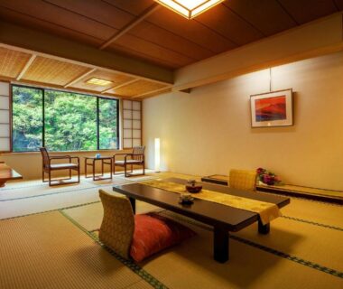Traditional tatami room with low table, cushions, sliding wooden screens and green view at Harataki in Fukushima