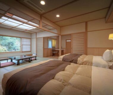 Tatami room with twin beds, shoji screens, low table and garden view at Harumiya Ryokan Fukushima