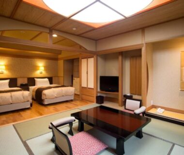 Tatami room with low table, zabuton chairs, twin beds and tokonoma at Harumiya Ryokan, Fukushima