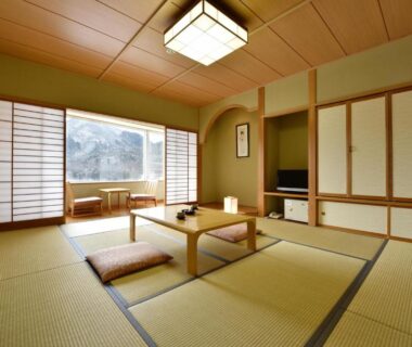 Traditional tatami room with low table, zabuton cushions, shoji screens and garden view at Harunako Onsen Yusuge Gunma