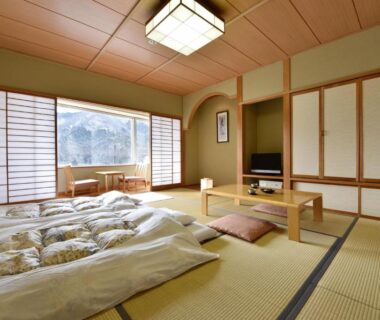 Tatami room with futon bedding, shoji screens and low table at Harunako Onsen Yusuge, Gunma