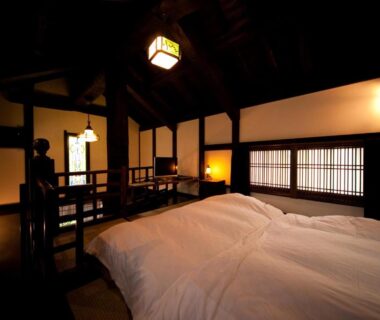 Dimly lit tatami room with futon bedding, shoji screens and wooden beams at Hatago Kayausagi in Ōita