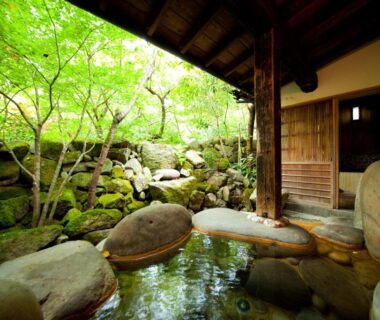 Stone-lined open-air onsen beside a mossy garden at Hatago Kayausagi, Oita, Kyushu