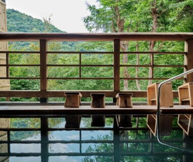 Outdoor onsen with wooden stools and forest view at Hatago Kintoen, Kanagawa, Japan
