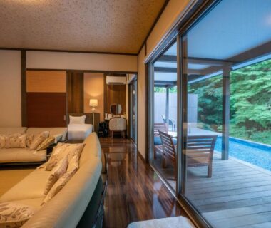 Tatami area and sofa opening to wooden deck and outdoor bath at Hatago Sakura in Oita, Kyushu, Japan