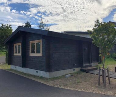 Single-story dark wood building with windows and walkway at Hatagoya Jozankei Shoten, Hokkaidō, Japan