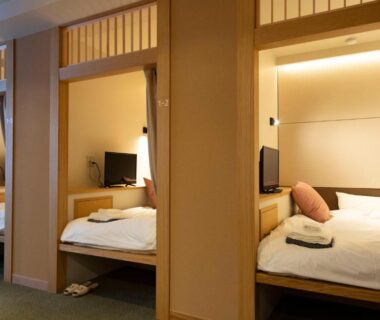 Three alcove beds with white linens, wood partitions and shoji-style transoms in ryokan guest room at Hatagoya Jozankei Shoten
