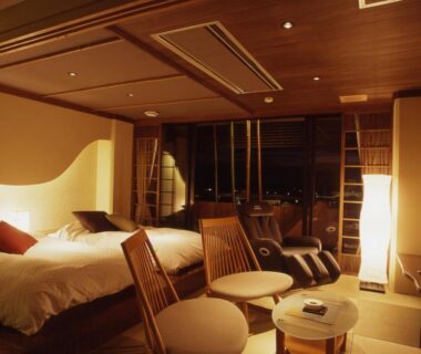 Two beds, low wooden chairs and soft lighting in Hatori ryokan room, Chūbu Ishikawa Japan