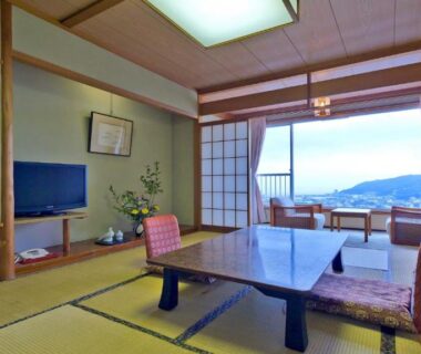 Traditional tatami room with low table, floor chairs, shoji screens and sliding doors opening to distant water view