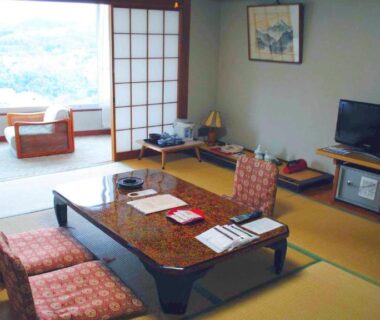 Tatami room with low table, floor chairs, shoji screens and window seating at Hatoya Hotel Shizuoka