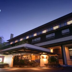 Evening facade with lit entrance and moon above, Hayamakan ryokan in Yamagata, Tōhoku, Japan