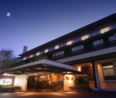 Evening facade with lit entrance and moon above, Hayamakan ryokan in Yamagata, Tōhoku, Japan
