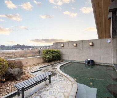 Rooftop outdoor onsen with stone paving, bench and garden shrubs at Healthy Pal Akagi in Gunma