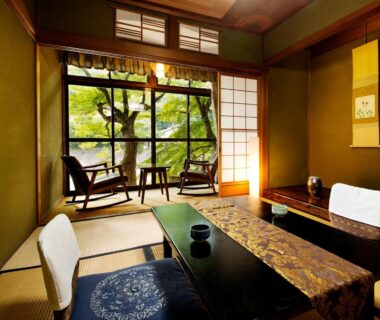 Tatami room with low table, shoji screens and seating overlooking leafy garden at Heihachi Tea House Inn in Kyoto
