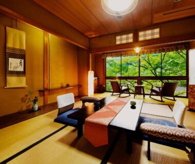 Traditional tatami room with low table, cushions and large window overlooking lush garden at Heihachi Tea House Inn, Kyoto