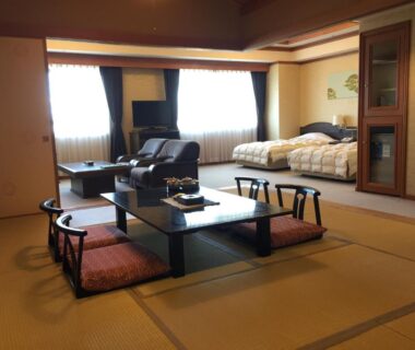 Tatami room with low table, zabuton cushions, sofa and twin beds at Heiseikan Kaiyotei, Hokkaidō