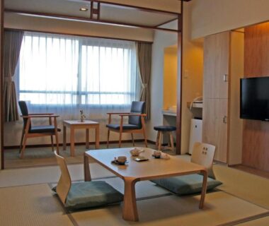 Traditional tatami room with low table, floor cushions, lounge chairs and window at Heiseikan Kaiyotei Hokkaidō
