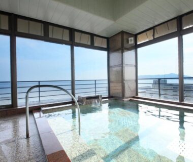 Indoor onsen bath with floor-to-ceiling windows overlooking coastal waters at Heiseikan Kaiyotei, Hokkaidō