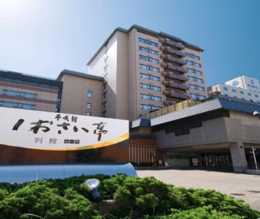 Multi-story ryokan exterior with large signboard and main entrance under clear sky in Hokkaidō