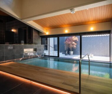 Indoor onsen pool with wooden deck and glass wall at Hibikino in Gunma, Kantō