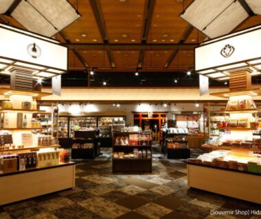 Interior of hotel souvenir shop with wooden shelves, display tables and traditional lantern lighting at Hida Takayama Green Hotel, Gifu