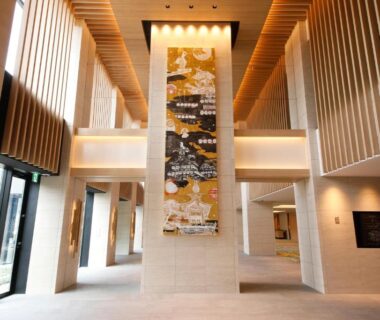 Bright lobby with tall wooden columns, hanging tapestry and modern reception area at Takayama Green Hotel, Gifu