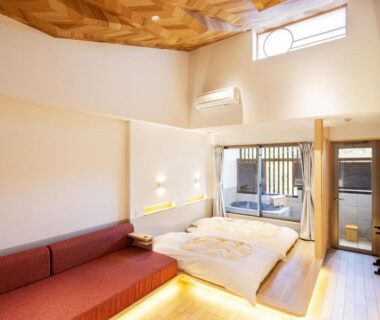 Bright tatami room with futon, low sofa and shoji doors leading to balcony at Hidamari Ichinoyu, Kanagawa